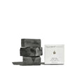 Stack of By Valenti black charcoal soap bars with a box labeled 'by valenti organics' on a white background