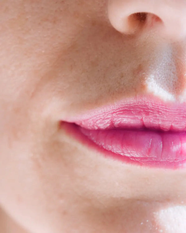 Close-up of a person's lips with pink lipstick on a blurred background