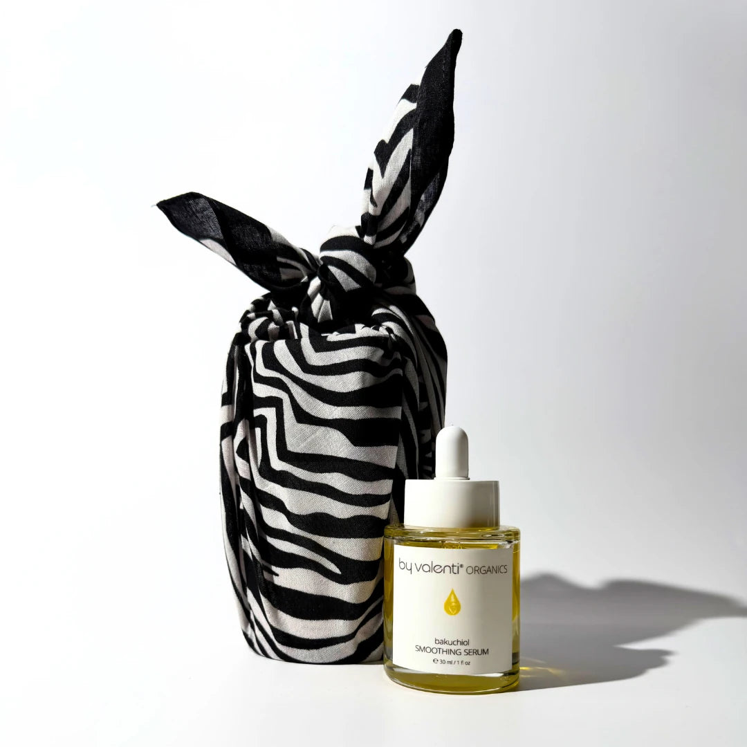Zebra-patterned furoshiki wrapped and bottle of By Valenti Organics Bakuchiol Smoothing Serum serum on a white background