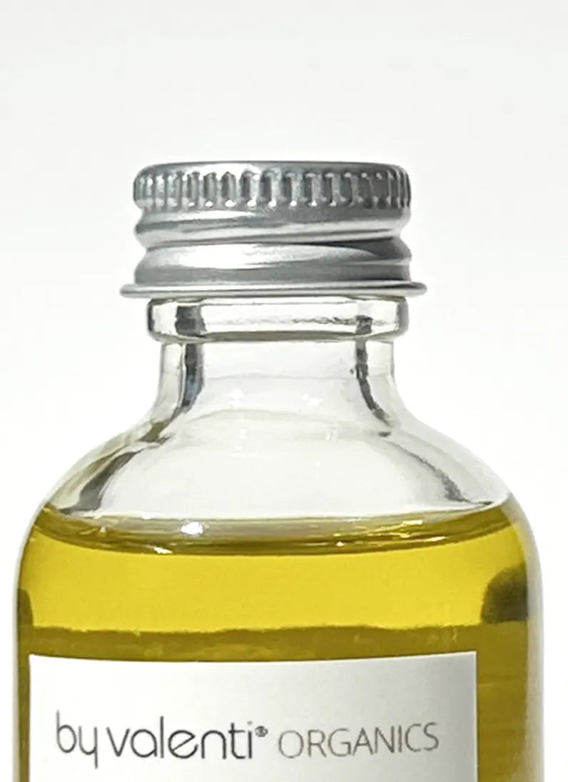 Close up of By Valenti Olive makeup remover with visible 'by valenti organics' brand and aluminium cap
