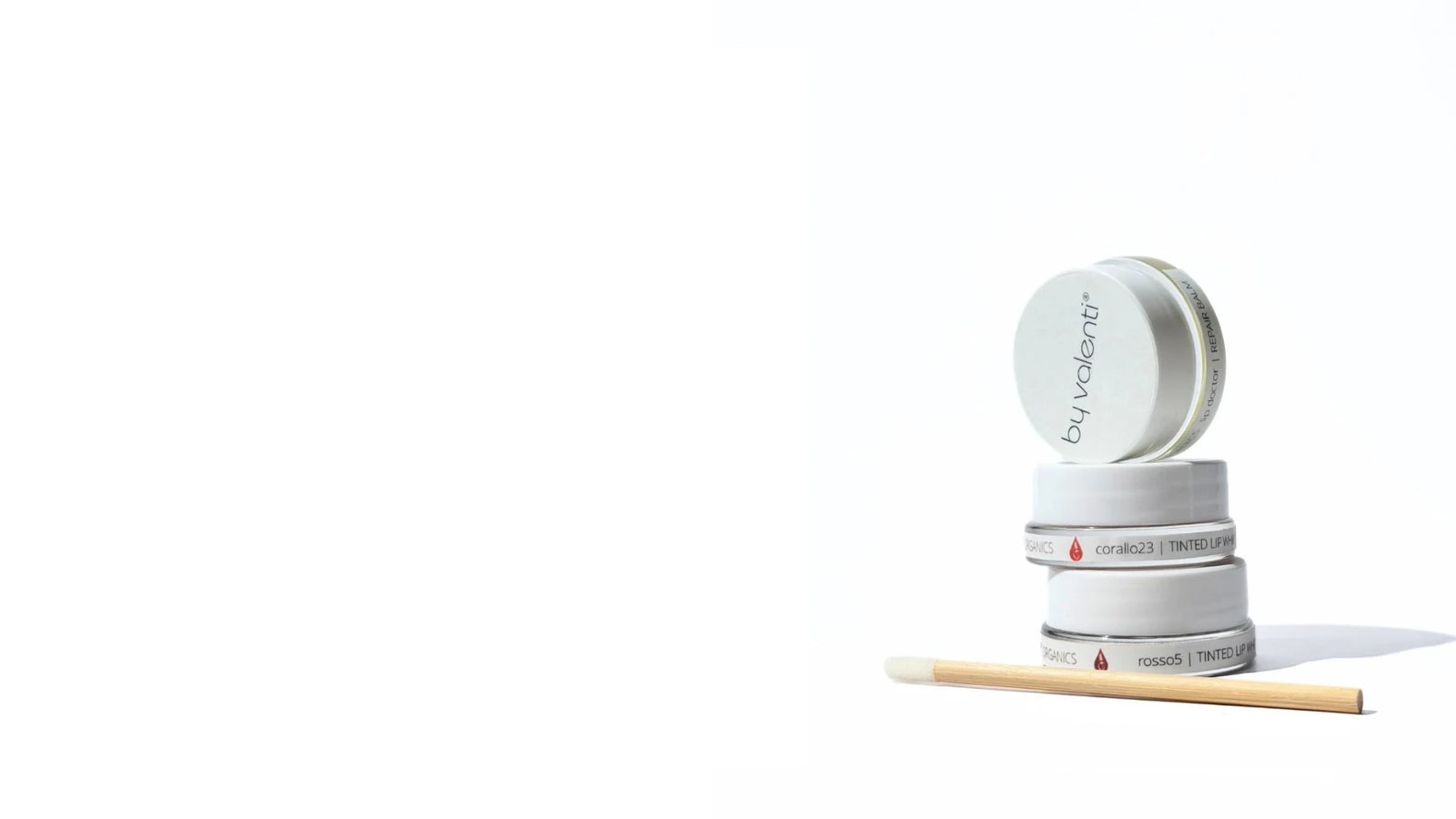 Stack of 3 jars of tinted lip whipped balms with an applicator wand on a white background