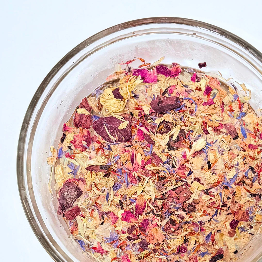 Bowl filled with colorful By Valenti Wildflowers facial tea in a glass bowl on a white background