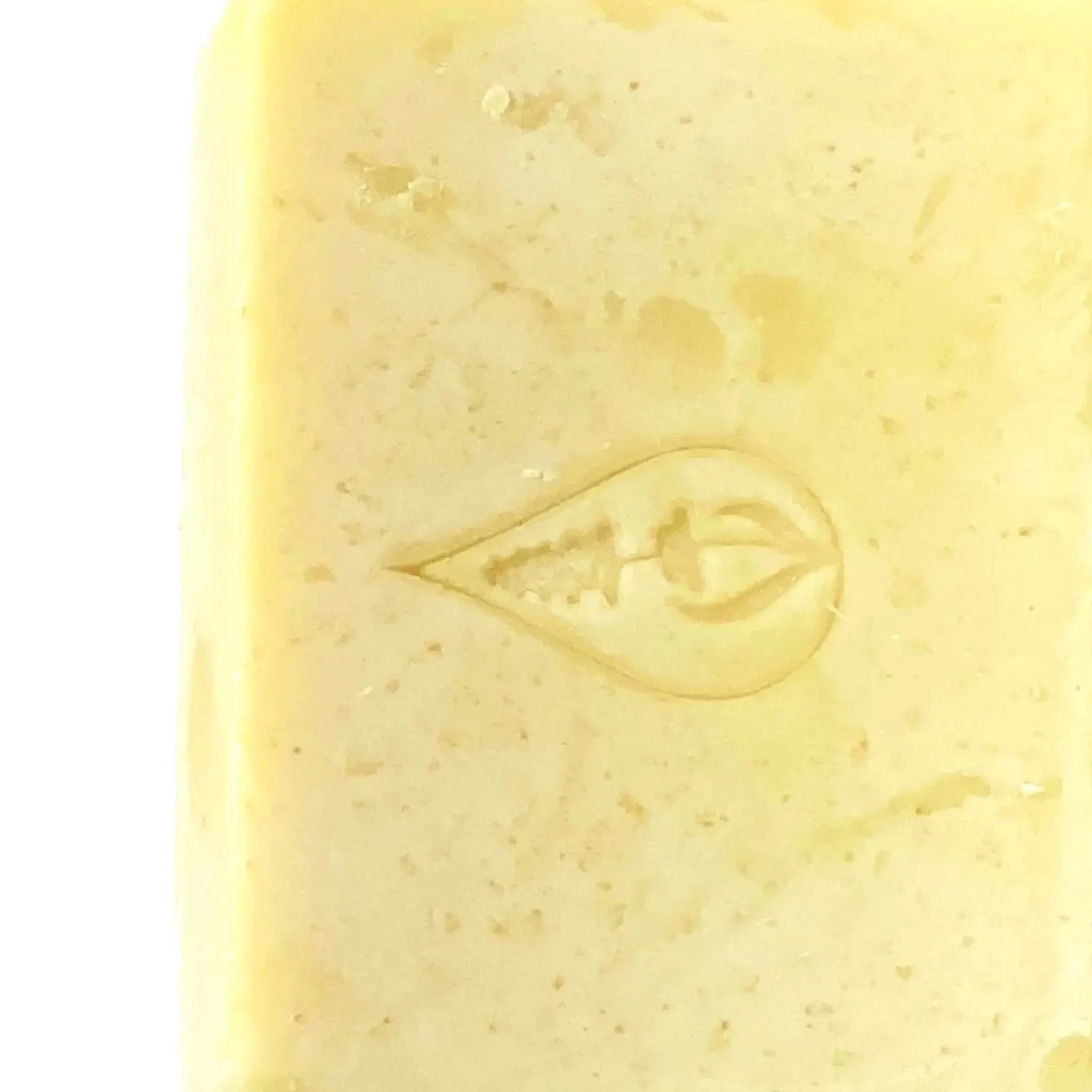 Close up of By Valenti butter yellow colored Chamomile Bar Soap with stamped logo on a white background