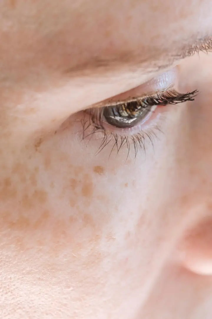 Close-up of a woman's eye with detailed eyelashes and skin texture.