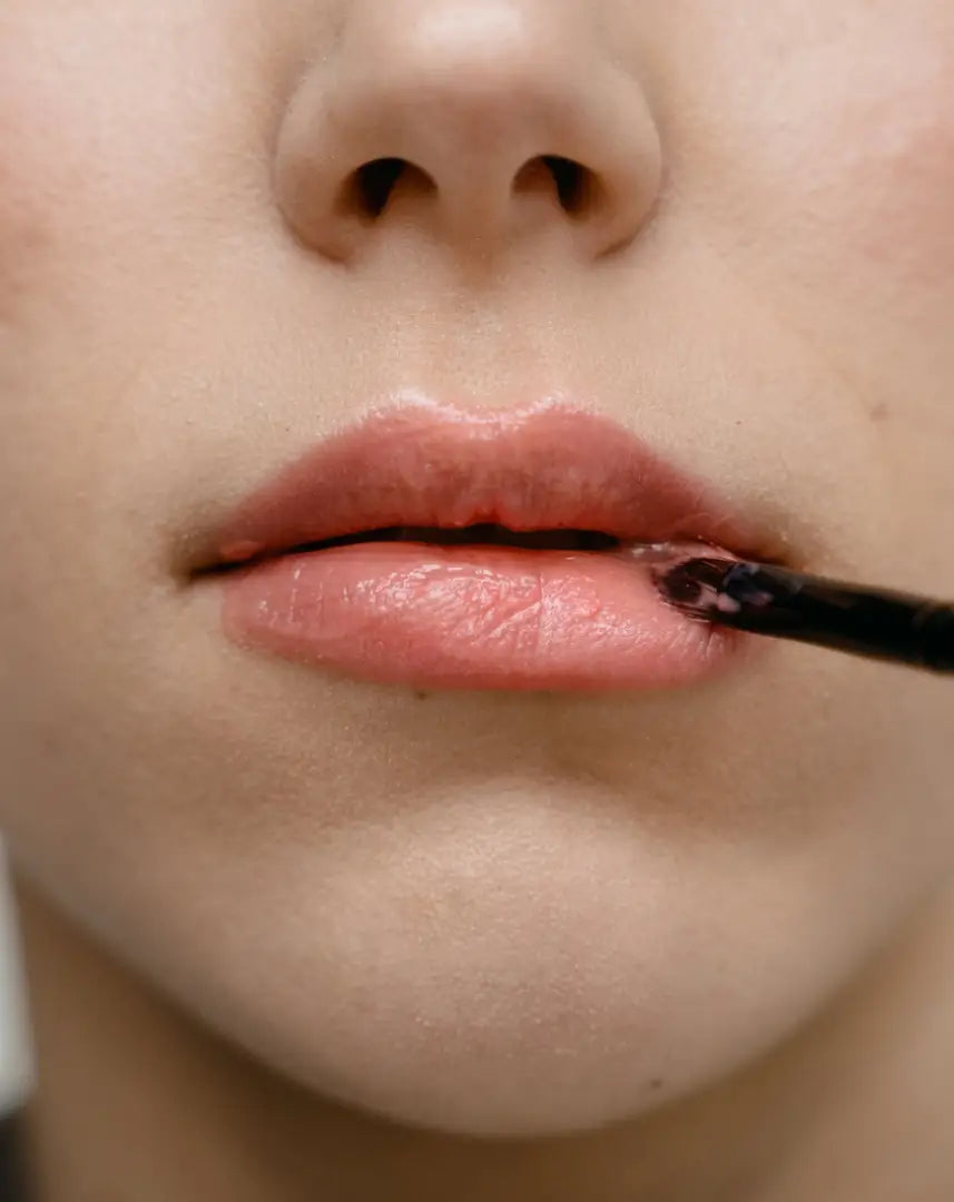 Close-up of a woman applying By Valenti's lip whipped souffle with a brush
